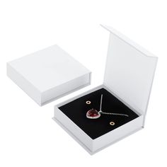 an open white box with a necklace in it and a red stone on the inside