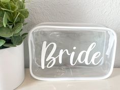 a clear plastic box with the word bride on it next to a potted plant