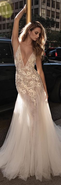 a woman in a white dress is standing on the street with her arms behind her head