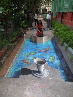 a woman sitting on the ground in front of a pool with fish painted on it