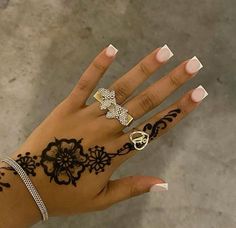 a woman's hand with tattoos and rings on it