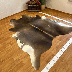 a cowhide rug is on the floor in front of a wooden floor with measuring tape