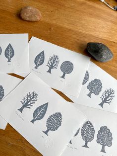 five cards with trees on them sitting on a table next to some rocks and scissors