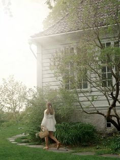 a woman is standing in front of a house with her hand on her hip and looking up at the sky