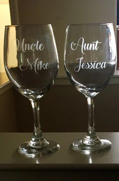 two wine glasses sitting on top of a table next to each other with the words uncle and aunt written on them