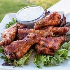 chicken wings with lettuce and dipping sauce on a white platter in the background