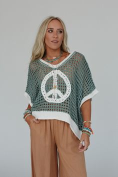 Cozy, cute, and embodying the perfect boho feel, the Peace Oasis Top brings all the peaceful vibes when you wear it! Comfy and cozy open knit fabric throughout Loose and slouchy silhouette for a relaxed fit Classic v-neckline and loose short sleeves for a comfortable, effortless look Contrast knit peace sign patchwork center design Slight high low bottom edge with ribbed knit trim along the bottom hem, sleeves, and neckline Pair with: Eye Of The Sun Padded Bralette, Frenchie Raw Edge Shorts and Bohemian V-neck Summer Sweater, Bohemian Textured Knit V-neck Top, Fall Beach Open Knit Top, Bohemian Knitted V-neck Top, Bohemian V-neck Knitted Top, Fall Beach Knit Top With Pointelle Knit, Casual V-neck Beach Poncho, Beach Sweater With Open Knit, Cozy Open Knit Beach Sweater