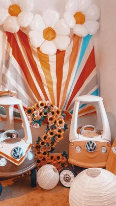 a bunch of fake flowers sitting on top of a table next to two vw campers