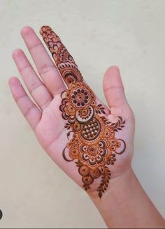 a hand holding a henna on it's palm with an intricately decorated design