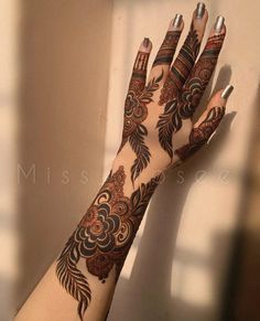 a woman's hand with hennap and flowers on her arm, against a white wall