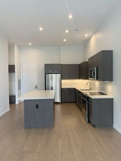 an empty kitchen and living room with wood flooring in the middle, including stainless steel appliances