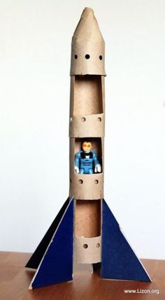 a paper model of a rocket ship with a small figure in the bottom section and an orange toy on top