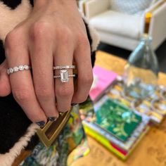 a woman holding onto her engagement ring while standing in front of a table with other items