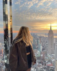 a woman standing on top of a tall building looking out at the cityscape