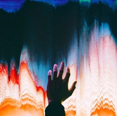 a person's hand reaching up into the air with colorful lights in the background