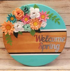 a wooden sign with flowers on it that says welcome spring