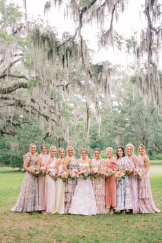 a group of women standing next to each other in front of a lush green field