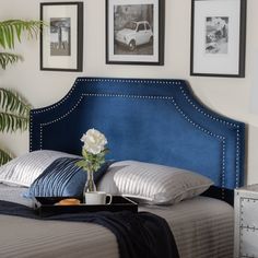 a blue headboard in a bedroom with pictures on the wall above it and a tray full of coffee