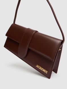 Find JACQUEMUS Le Bambino Smooth Leather Bag on Editorialist. The JACQUEMUS Le Bambino bag is crafted from smooth leather and features a flap closure with a metal logo detail. The bag has a single top handle and a detachable shoulder strap. The dimensions of the bag are 13.5cm in height, 28cm in width, and 5cm in depth. The handle drop is 21cm. Jacquemus Le Bambino Long, Ski Accessories, Brown Bags, Flat Espadrilles, Metal Logo, Swim Accessories, Heeled Loafers, Metallic Logo, Pink Bag