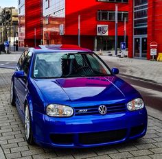 a blue car is parked in front of a red building