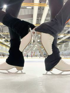 two people wearing ice skates on an indoor rink