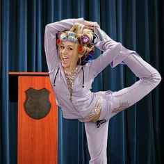 a woman is doing yoga in front of a podium with her hands on her head