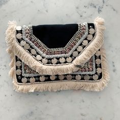 a black and white purse on a marble surface with beads, fringes and pearls