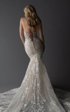 a woman in a wedding dress with an open back and floral appliques on it