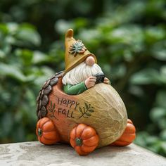 a statue of a gnome sitting on top of a rock with the words happy fall written on it