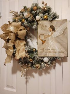 a christmas wreath with an angel on it and a card hanging from the front door