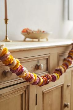 a garland is hanging from the side of a dresser in front of a bowl and candle