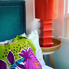 a lamp that is sitting on top of a table next to a bed with pillows