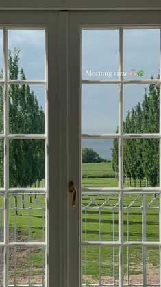 two open windows overlooking a grassy field and trees