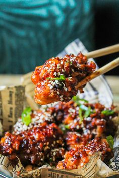 two chopsticks with meat on top of some food in a glass bowl next to a person