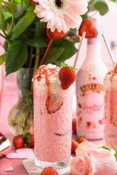 strawberry mousse in a tall glass with strawberries on the rim and flowers behind it