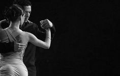 a man and woman dance together in the dark, with their arms around each other