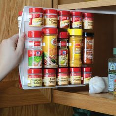 a person is picking up some spices from the shelf in front of their kitchen cabinets