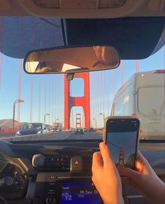 someone is using their cell phone while driving over the golden gate bridge