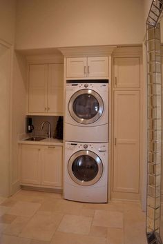 a washer and dryer are in the corner of a kitchen with white cabinets