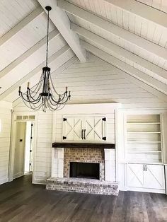 an empty living room with white walls and wood floors, a chandelier hanging from the ceiling