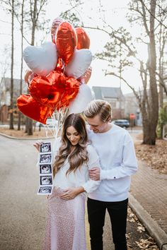 a man and woman standing next to each other holding balloons