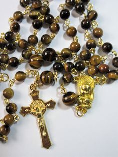 "This Tiger's eye Catholic rosary is made with Grade a gemstones. The hand turned links are gold plated as is the connector. The golden cross is from Italy. The rosary measures 26\" in the body and has a 5\" cross drop. This rosary will be slipped into a velvet bag and shipped in a bubble mailer." Gold Spiritual Rosary Bracelet With Polished Beads, Gold Rosary Bracelet With Gemstone Beads, Gold Rosary Bracelet With Natural Stones And Round Beads, Gold Rosary With Gemstone Beads Gift, Gold Cross Rosary In Spiritual Style, Gold Cross Rosary, Gold Rosary Bracelet With Cross And 8mm Beads, Spiritual Gold Rosary With 8mm Beads, Gold Spiritual Rosary With Gemstone Beads