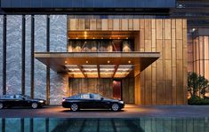 two cars are parked in front of a building with an entrance and water reflection on the ground