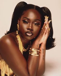 a woman wearing gold jewelry and bracelets posing for a photo with her hands on her face