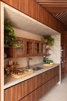 a kitchen with wooden cabinets and counter tops next to a plant on the counter top