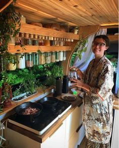 a woman standing in front of a stove top oven holding a wine glass and pot