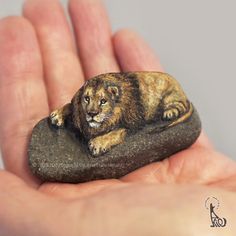 a small lion figurine sitting on top of a rock in someone's hand