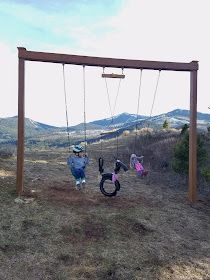 two children are playing on swings in the mountains