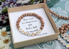 a wooden beaded bracelet with white and gold beads in a box on a lace tablecloth