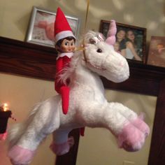 an elf riding on the back of a white unicorn toy hanging from a ceiling in a living room